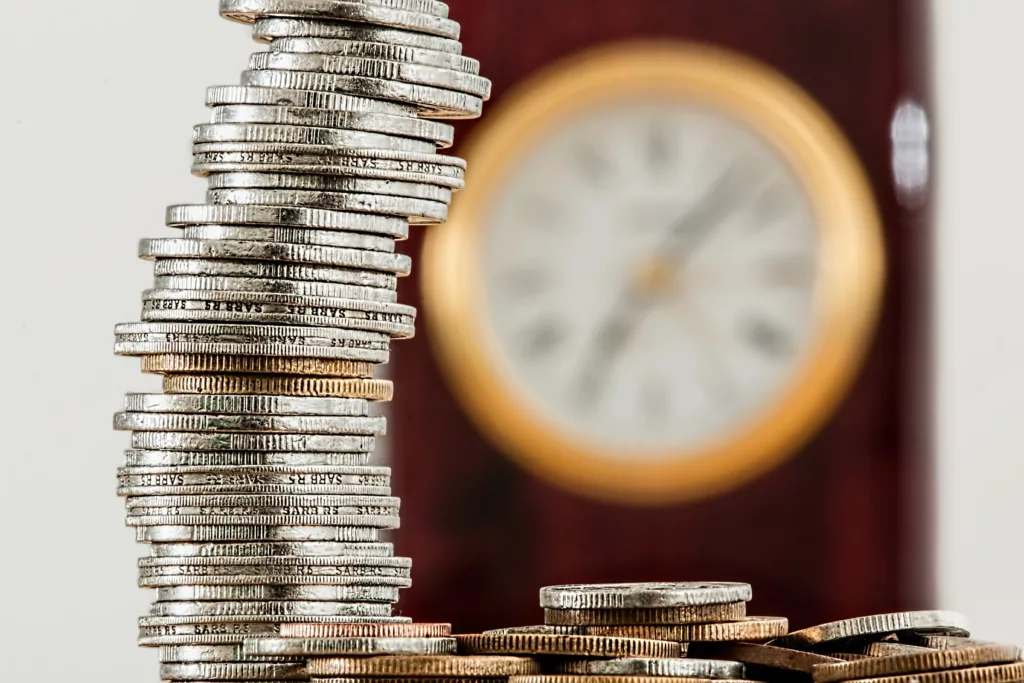 coins on a pile with the clock in the background