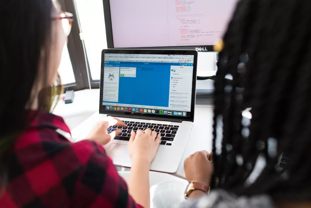 Two people looking at one laptop, working.
